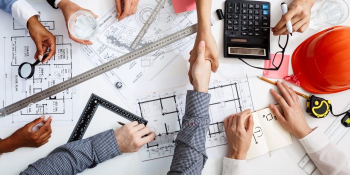 Picture of businessmen's hands on white table with documents, coffee and drafts
